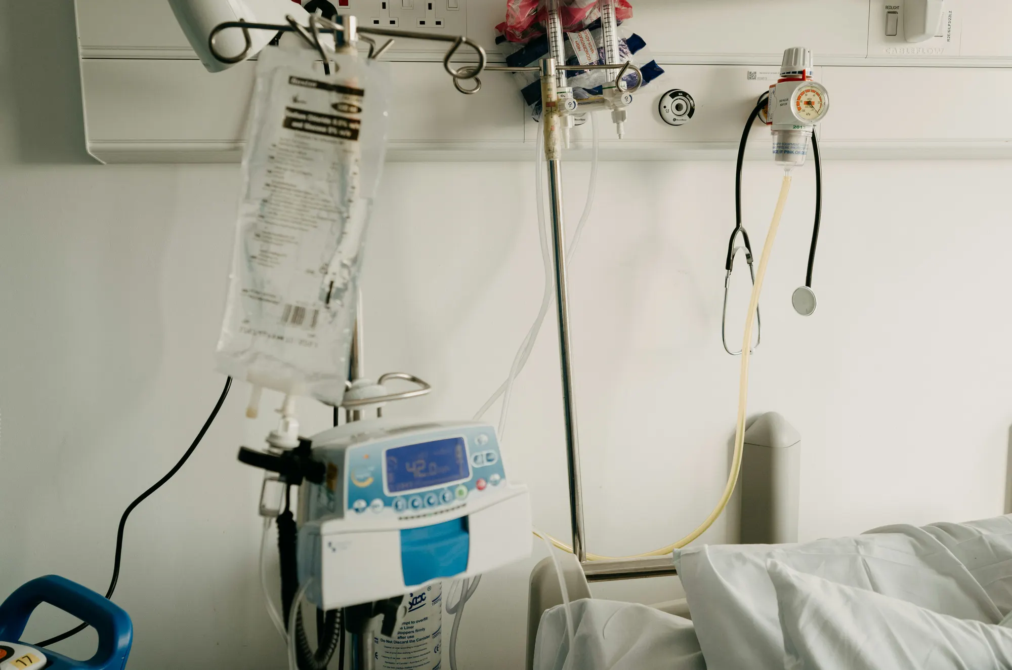 A hospital bedside with an IV line, infusion pump, and stethoscope
