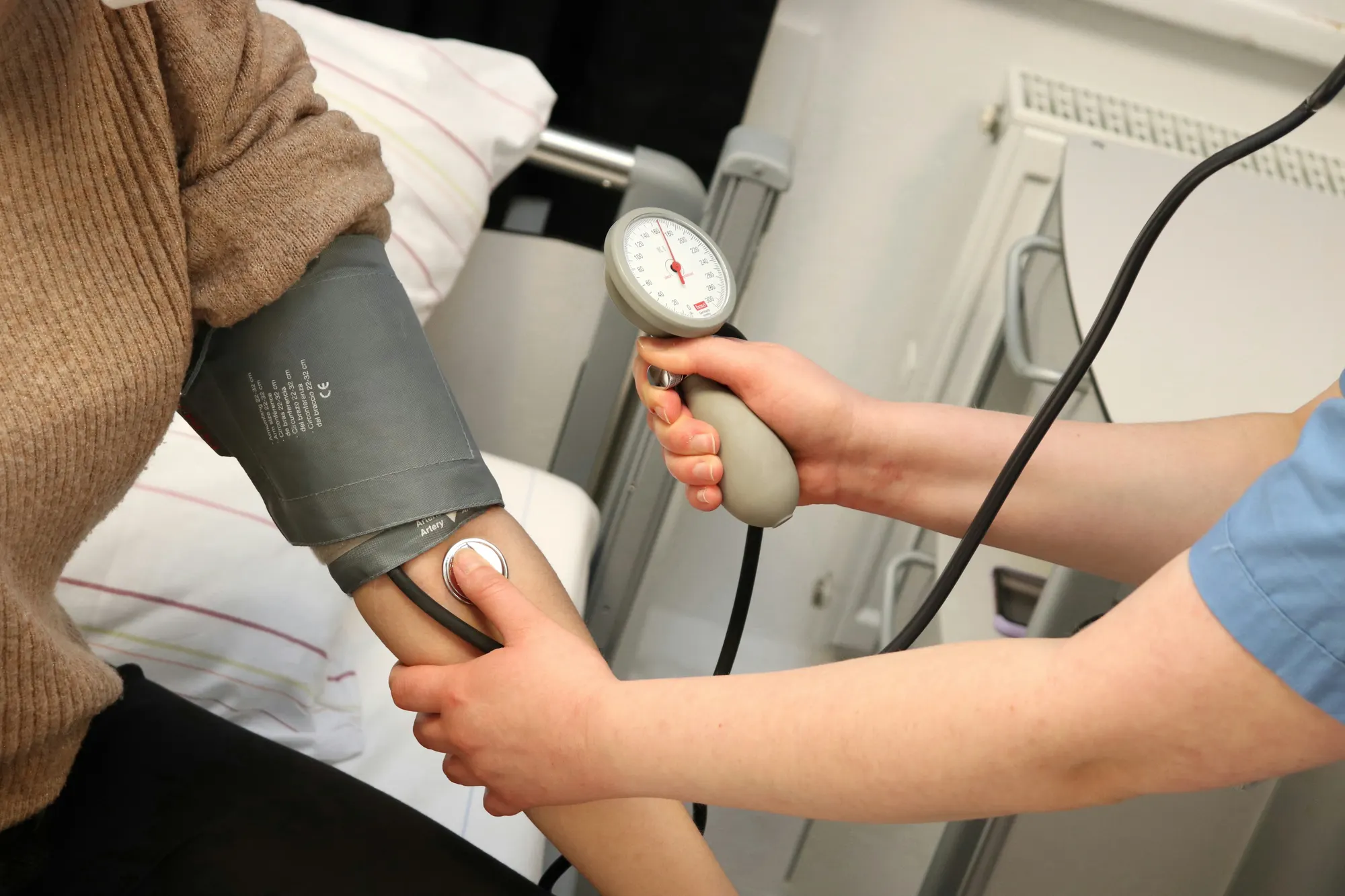 A clinician taking a patient’s blood pressure in an exam room